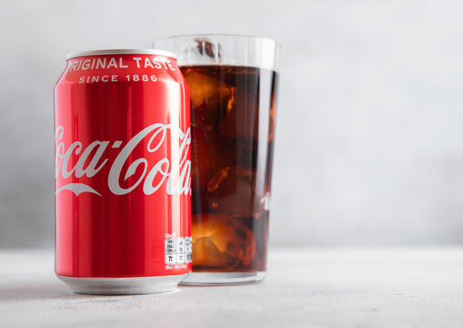 LONDON,UK - JULY 01,2025: Aluminium can of Original taste Coca Cola soft soda drink with glass of ice cubes on light table background.