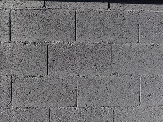 Concrete block wall presenting a rough grey texture, creating a robust background with an industrial feel, ideal for building themes and graphic design elements © Tetyana