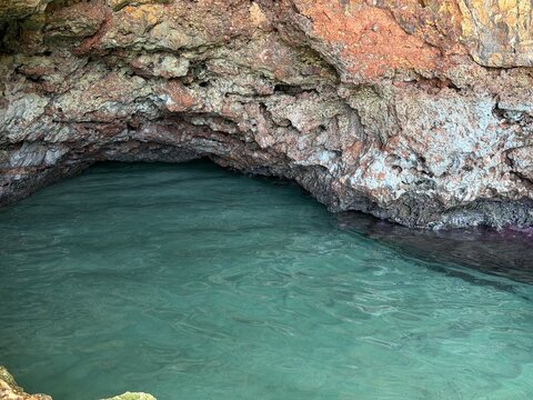 Natural sea cave entrance revealing clear turquoise water, a hidden grotto in the rocky coastline of manacor, balearic islands, spain, inviting exploration
