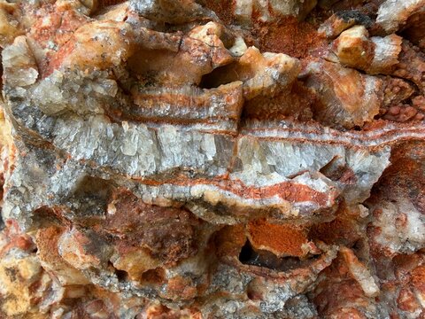 Natural rock formation displaying clear crystal deposits with reddish iron oxide streaks, creating unique geological patterns and mineral textures in manacor, balearic islands, spain