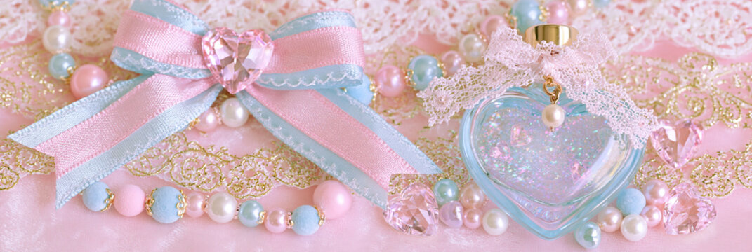Herzf&ouml;rmige Parf&uuml;mflasche zwischen rosa und blauen Weihnachtskugeln mit Glitzer und Schleifen