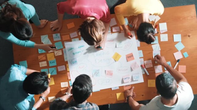 Top view of project manager writing and sticking stick notes. Aerial view of professional business people working together planning strategy while drafting mind mapping at meeting room. Symposium.