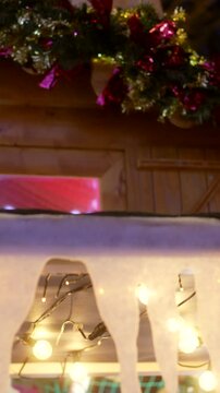 Detailed view of a wooden chalet at a christmas market, beautifully decorated with a cartoon santa claus figure, festive garlands, twinkling lights, and artificial snow and icicles