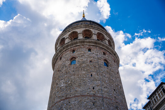Galata Tower in Istanbul, Turkey, a historic stone structure with a conical roof surrounded by modern buildings and a blue sky
