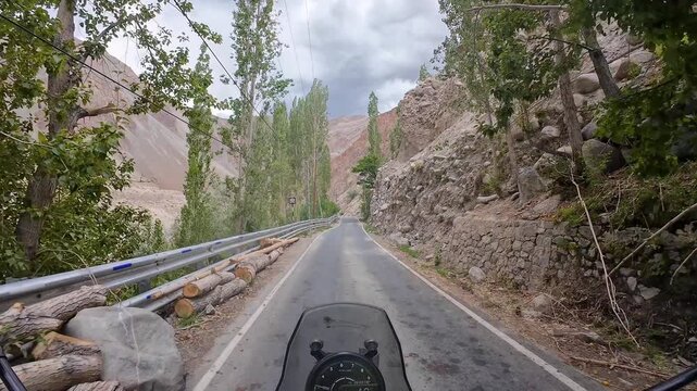 Dah Hanu valley, India : Point of view footage of motorcycle rides on narrow road in Aryan valley in Ladakh, India surrounded by arid mountain under dramatic cloudy sky