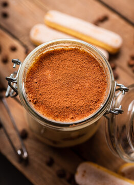 Homemade tiramisu in glass jar on rustic wooden background. Cooking recipes. Selective focus.