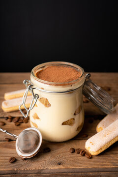 Homemade tiramisu in glass jar on rustic wooden background. Cooking recipes. Selective focus.