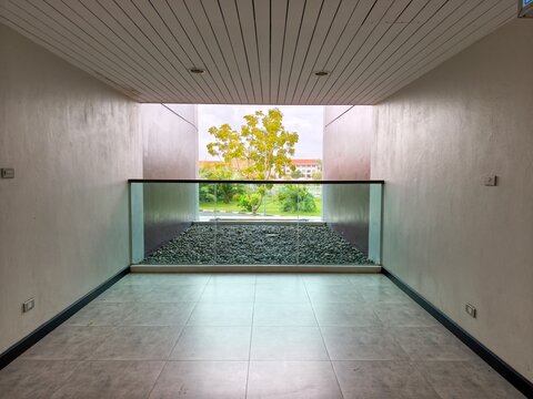 Modern empty balcony corridor with tiled floor and minimalist frame view overlooking gravel garden and green tree
