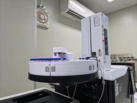 Automated gas chromatography system with a rotating autosampler tray and sample vials operating inside a modern analytical chemistry laboratory for precise scientific testing and chemical analysis.