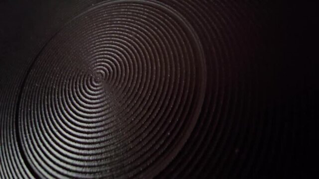 Detailed close-up of a dark circular spiral heating plate on an electric stove, highlighting industrial design, metallic ridges, and heat distribution surface.