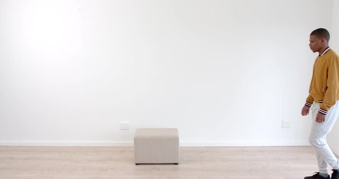 African American man practicing balance exercises on step stool in minimalist room