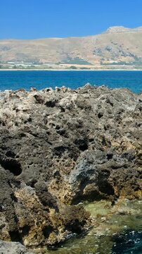 Vertical video of rocky shore of Crete Island with turquoise clear Mediterranean sea water. Greece.
