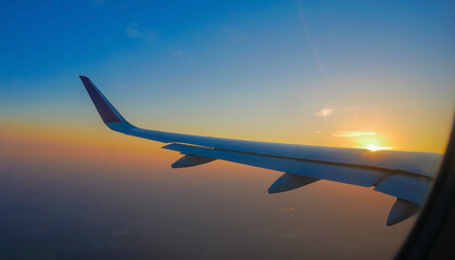 View from airplane window looking out at aircraft wing during a beautiful pastel sunset scene © SASITHORN