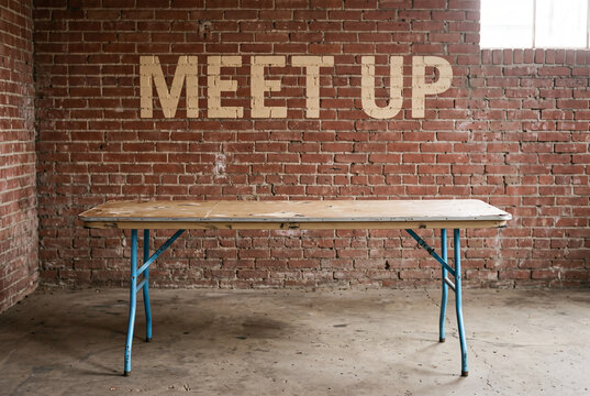 Meetup event concept with folding table against rustic brick wall