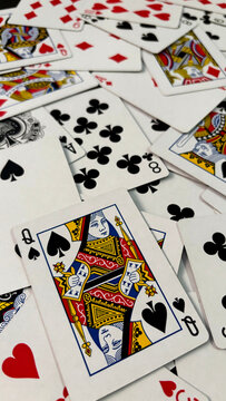 Queen of spades playing card lying on scattered deck of cards background