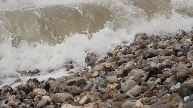 A wave from the French Atlantic slow motion rolls onto the pebble beach