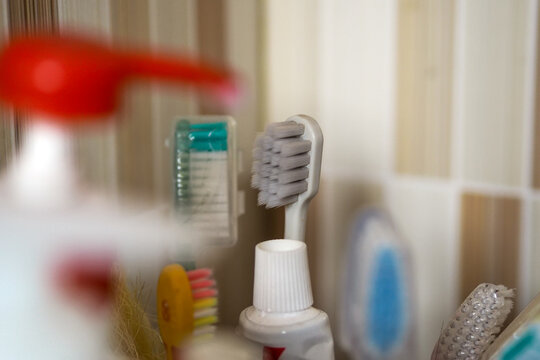 close-up shot of personal hygiene items including a toothbrush and toothpaste tube in a bathroom setting, with shallow depth of field.