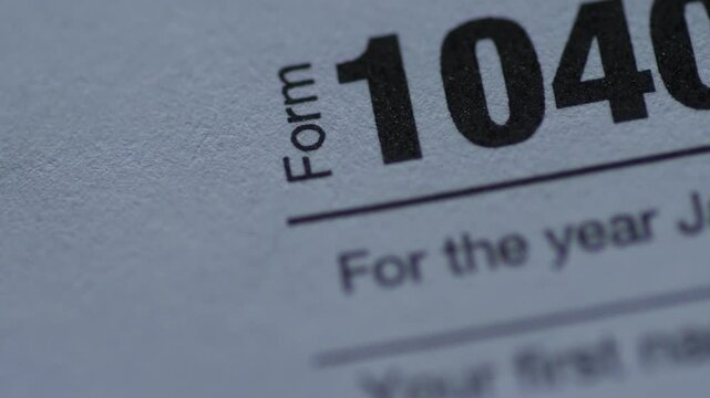 Close-up view of the official US Individual Income Tax Return Form 1040. The video clip showcases Internal Revenue Service paperwork for financial reporting and federal tax payment