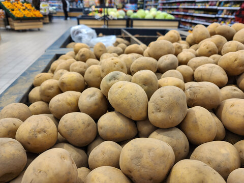 Potatoes filling a display bin in a supermarket produce aisle, offering a healthy and raw food choice for customers shopping for fresh vegetables