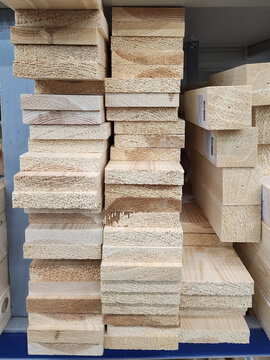 Lumber boards and wood planks creating a full storage rack, representing construction materials, home improvement, and timber supplies in a retail hardware environment. Vertical photo