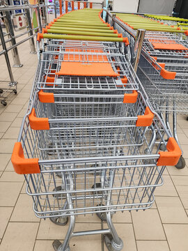 Many empty shopping carts are neatly nested in rows, waiting for customers at the entrance of a grocery store, representing consumerism and retail logistics. Vertical photo