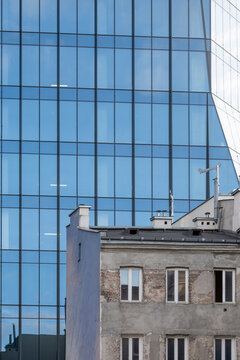 Historic residential building contrasted with a modern blue glass tower in Warsaw Poland showing layers of old and new urban architecture