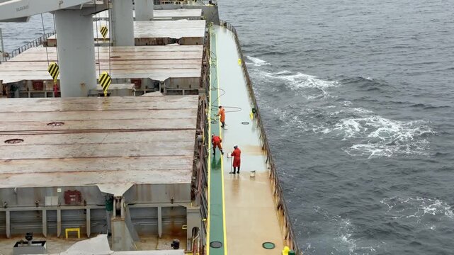 vessel at sea and crew members moping deck with chemicals for remove rust sediment