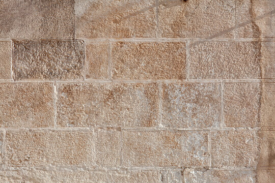 Close-up of marnous calcarenite ashlar blocks showing intergranular porosity, tool marks, carbonate grain structure, and differential weathering typical of Apulian limestone masonry.