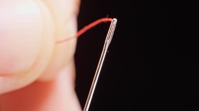 Extreme Macro View of Fingers Failing to Insert Red Thread through Needle Eye, Difficulty with Sewing, Precision and Poor Eyesight