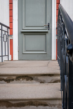 Gray Front Door Above Weathered Concrete Steps with Black Railings