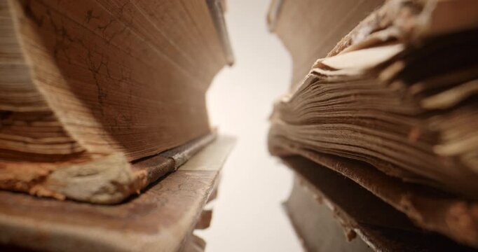 Cinematic slow push-in through stacks of old vintage books, filmed with a probe lens. Detailed close-up perspective of aged book spines and pages creates an atmospheric visual representing education