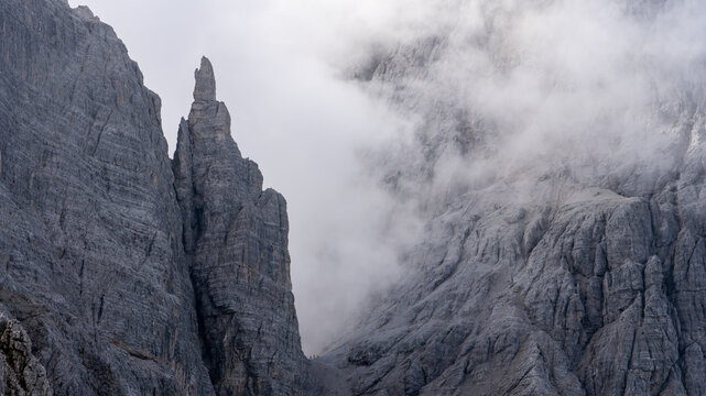 Wanderer in einem Sattel unterhalb zackiger Berggipfel geh&uuml;llt in Wolken (Sextener Dolomiten)