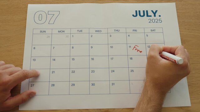 Person writes &ldquo;Free&rdquo; on all available days in a monthly calendar while organizing personal availability and planning upcoming free time.