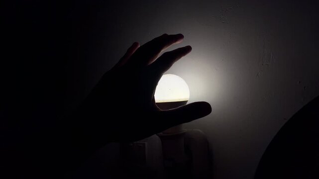 hand blocking bright light source in dark room