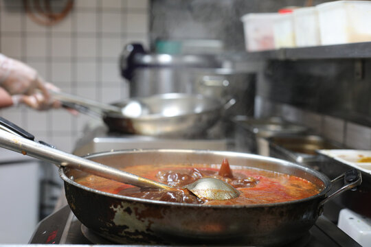 Pr&eacute;paration de plats dans une cuisine professionnelle avec une po&ecirc;le sur le feu