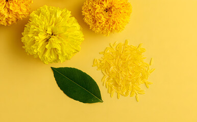 Obraz premium Joyful Dussehra. Yellow blooms, emerald foliage, and a rice pattern on a yellow backdrop. Conceptual representation of the Indian festival.