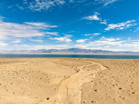 winding dirt road through desert landscape leading to lake and distant mountains
