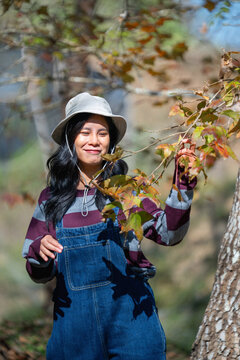 Young woman smiles beside autumn tree