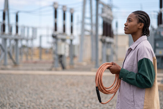 Power substation worker holding cable in utility yard