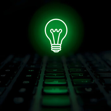 Glowing green light bulb icon hovering over computer keyboard represents creative idea generation problem solving and innovative brainstorming technology solutions.
