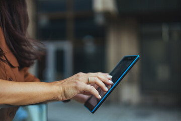 Woman Using Tablet Touchscreen Outdoors With Hands Typing On Blue Digital Device For Work © Dragana Gordic