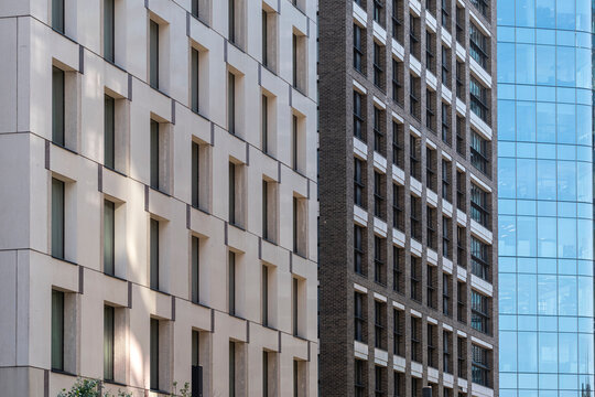 Modern facades in London England create an urban composition of repeating windows geometric forms and a blue glass tower showing architecture and density