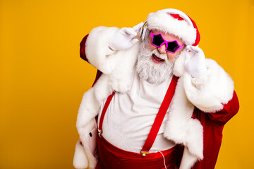 Naklejka premium Santa Claus in festive red suit wearing headphones and pink star sunglasses dancing to music at a playful Christmas party celebration