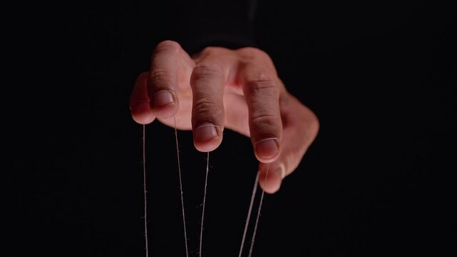 Eerie Puppeteer Hand Holds Invisible Puppet Strings against Black Background, Symbolizing Leadership Manipulation, Power and Control over Human Lives