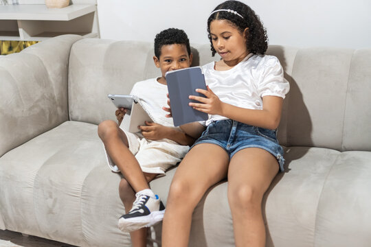 Children using digital tablets on sofa at home