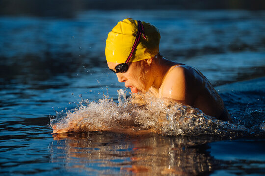 White swimmer performing breaststroke in open water with yellow cap