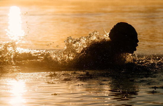 White person swimming with splashing water at sunset in the USA