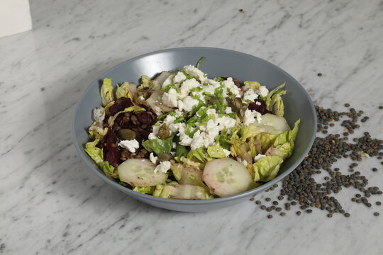Salade avec laitue, concombres et fromage sur une table en marbre