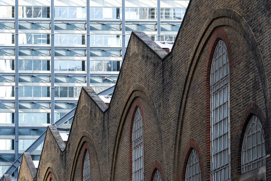 Historic brick gables beside a modern glass building create architectural contrast between industrial heritage and contemporary urban development