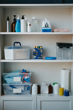 Vertical image of medical supplies, test tubes, bottles, containers organized on shelves. Visual suitable for clinic management, healthcare stock, laboratory concepts
